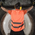 Replacing Heavy Equipment Tire Concept. Caucasian Machinery Operator and the Heavy Duty Wheel.